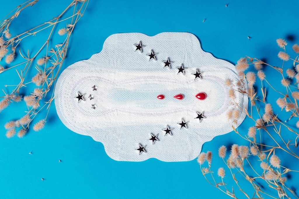 foto de um absorvente com estrelas nas bordas e 3 pingos de sangue no centro