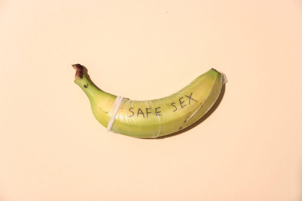 banana com casca escrita "safe sex" e vestida com camisinha.