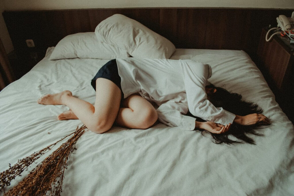 mulher deitada em posição fetal em uma cama