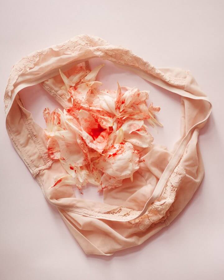 Calcinha com pétalas de rosa sujas de vermelho (imitando sangue da menstruação)