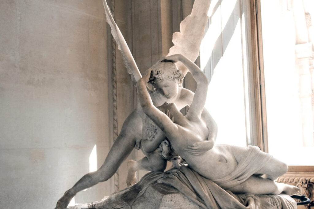 Estátua de Eros (ou Cupido) e Psique. Eros tem asas e está segurando sua amada. Psique está olhando pro rosto de Eros e segurando sua cabeça. Eles parecem estar prestes a se beijar.