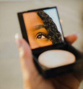 rosto de uma mulher refletido em um espelho de bolsa